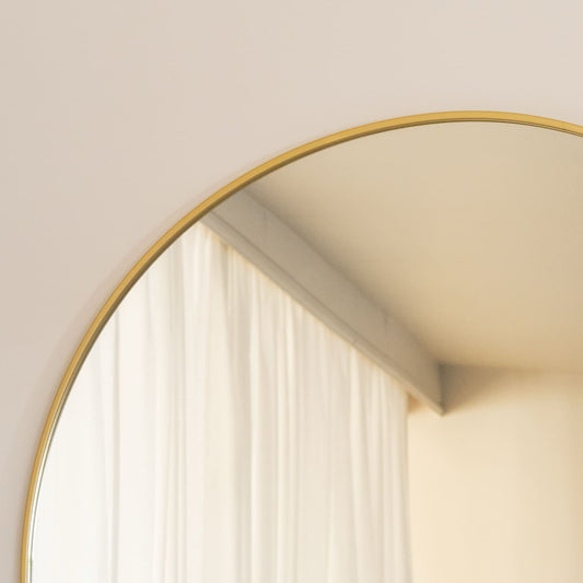 Arched gold mirror leaning against a wall